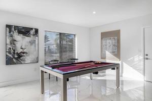 een pooltafel in een witte kamer met schilderijen bij Villa RendezVous- Stunning 4BDR with Pool by VIAC in Fort Lauderdale