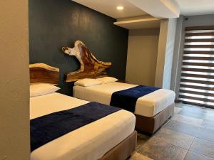 een slaapkamer met 2 bedden en een houten hoofdeinde bij Hotel La Bikina in Tequila