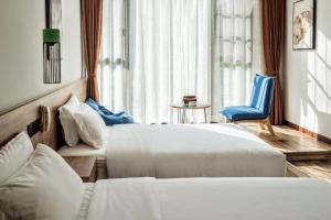 um quarto de hotel com duas camas e uma cadeira azul em National Forest Park(Yangjiajie ) MINI Inn em Zhangjiajie
