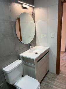 uma casa de banho com um WC branco e um espelho. em Casa del Alto, a estrenar, 3 dormitorios, 2 baños em Esquel