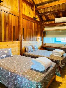two beds in a room with wooden walls at Wooden Homestay Đại Lải in Phúc Yên