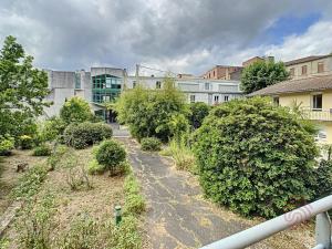 a street in a city with bushes and buildings at Charmant F2 climatisé avec terrasse, proche Thermes, parking privé, animaux acceptés - FR-1-451-163 in Lamalou-les-Bains