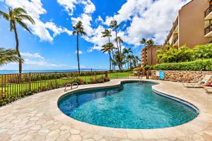 a swimming pool with palm trees and a building at Maalaea Banyans 314 in Wailuku
