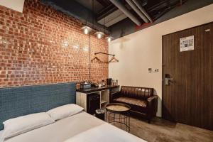1 dormitorio con pared de ladrillo, cama y silla en Hotel Leisure Chiayi en Chiayi
