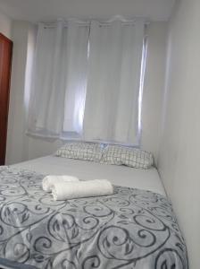 a bed with a towel on it with a window at KITNET MOBILIADA - PENHA in Rio de Janeiro