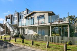 a large house with a fence in front of it at The White Haus - Waihi Beach Upstairs Holiday Unit in Waihi Beach