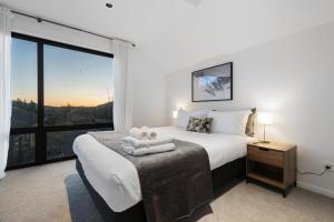 a bedroom with a bed and a large window at Cardrona Creekside Apartment in Cardrona