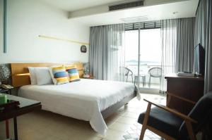 a hotel room with a bed and a balcony at Baboona Beachfront Living in Pattaya