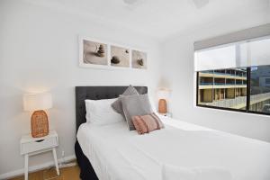 a white bedroom with a large white bed and a window at Avilla Court Stunning Views in The Entrance