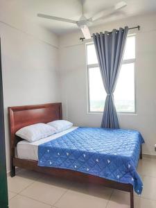 a bedroom with a bed with a blue comforter and a window at Meru View in Ipoh