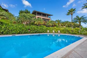 a swimming pool in front of a house with palm trees at Kapalua Ridge Villa 2622 in Kahana