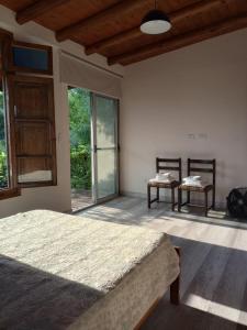 a bedroom with a bed and two chairs and windows at Chacras casa Armonia in Chacras de Coria