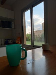 uma chávena de café verde sentada numa mesa em frente a uma janela em Chacras casa Armonia em Chacras de Coria