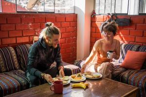 Duas mulheres sentadas à mesa a comer comida. em Aldos Guest House em Huaraz