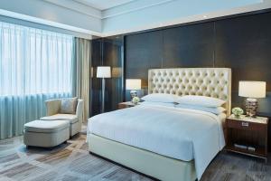 a bedroom with a large white bed and a chair at Zhuzhou Marriott Hotel in Zhuzhou
