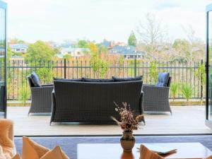 un patio con muebles de mimbre en una terraza de madera en Wonderful River View-Brand New Home - 4 Bedrooms en Hamilton