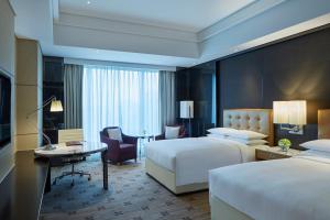 a hotel room with two beds and a desk at Zhuzhou Marriott Hotel in Zhuzhou