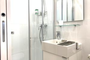 een witte badkamer met een wastafel en een douche bij M2 Cosy studio RER BC500m Orly 20 min Netflix in Massy