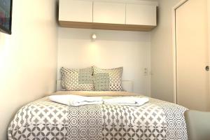 een kleine slaapkamer met een bed met zwart-wit beddengoed bij M2 Cosy studio RER BC500m Orly 20 min Netflix in Massy