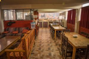 un restaurante con mesas y bancos de madera y una sala con mesas en Aldos Guest House, en Huaraz