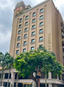 um grande edifício com uma árvore em frente em Chong Yu Hotel em Taoyuan