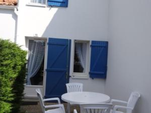 een tafel en stoelen met blauwe luiken op een wit gebouw bij Maison La Faute-sur-Mer, 2 pièces, 4 personnes - FR-1-476-203 in La Faute-sur-Mer