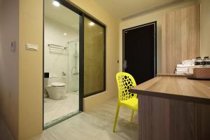 a bathroom with a yellow chair and a sink and a toilet at 花蓮知卡宣民宿 in Jian