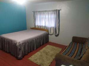 a room with a bed and a window and a chair at mini-hogar en santa teresa in Santa Teresa