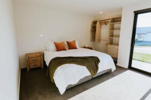 a bedroom with a large bed and a window at On The Rocks - Sleeps 8 - Family Friendly Holiday Home in Paraparaumu Beach
