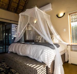 Un dormitorio con una cama blanca con dosel. en Buhala @ 411, en Hoedspruit 70 fotos más