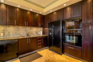 eine Küche mit Holzschränken und schwarzen Geräten in der Unterkunft Kapalua Golf Villa 16V 2 in Kahana + 31 Fotos