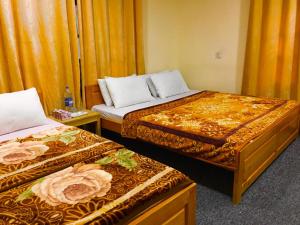 Habitación de hotel con 2 camas y cortinas de color naranja en Chitral Inn Resort (Kalash Valley), en Chitral