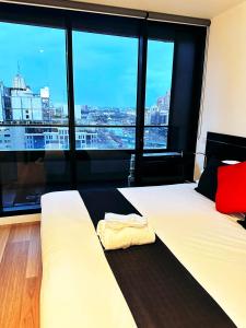 1 Schlafzimmer mit 2 Betten und einem großen Fenster in der Unterkunft Aura on Flinders Serviced Apartments in Melbourne