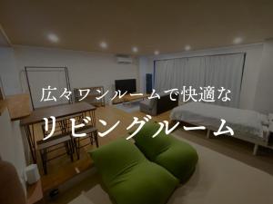 Apartment Goto アパートメント五島 في غوتو: غرفة معيشة مع أريكة خضراء وسرير