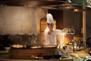 un chef de pie en una cocina preparando comida en The Ritz-Carlton Beijing, en Beijing