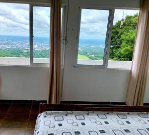 a bedroom with two windows and a bed with a view at Finca la Aurora in Villavicencio