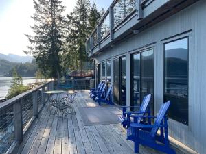 a deck with blue chairs and a table and windows at Earls Cove Orca View in Egmont