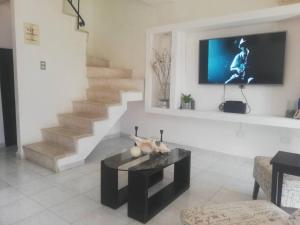 a living room with a table and a tv on a wall at Casa de Cielo y Mar en Cancún in Cancún