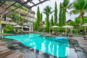 a swimming pool at a resort with chairs and umbrellas at KajaNe Mua at Ubud Bali in Ubud