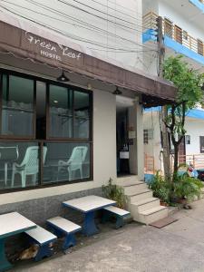 a green yard house with two picnic tables outside at Green Leaf Hostel in Phuket