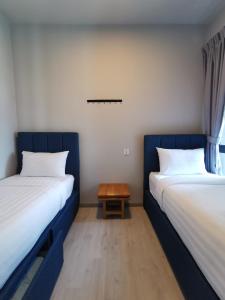 two beds in a room with a table between them at Kota Kinabalu Jesselton Quay Seaview with washing machine in Kota Kinabalu