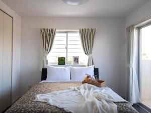 Un dormitorio con una cama con almohadas blancas y una ventana en Dolcevita, en Ginoza