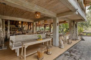 烏布的住宿－Joglo Organik Guesthouse，户外餐厅设有长凳和桌子
