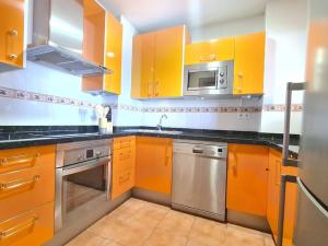 une cuisine avec des armoires orange et un appareil en acier inoxydable dans l'établissement 1HAB en Castillo Santa Clara, à Torremolinos