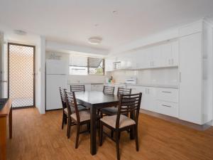 a kitchen with white cabinets and a table and chairs at Levuka Unit 12 14 Moreton Pde in Caloundra