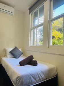 a bed with two pillows on it in a room with two windows at Gamma Hotel in Auckland