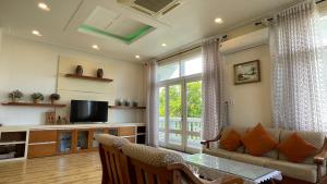 a living room with a couch and a tv at Villa Mui Ne Phan Thiet SeaView in Mui Ne