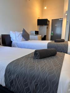 two beds in a hotel room with two mattresses at Gamma Hotel in Auckland