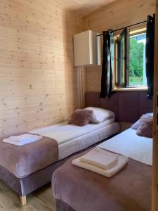 two beds in a room with wooden walls and a window at Las i woda in Przywidz