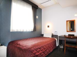 Schlafzimmer mit einem Bett, einem Schreibtisch und einem Fenster in der Unterkunft Hotel Trend Nishi Shinsaibashi in Osaka